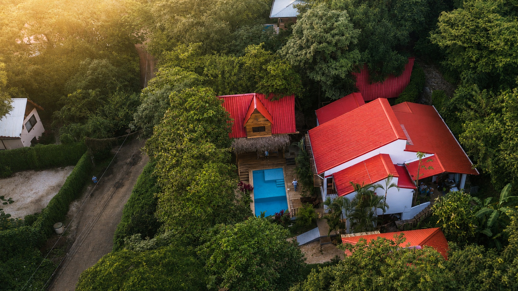 Aerial view of Hacienda Nosara — red-roofed Casa Brisa, the treehouse over the pool, and the studios nestled in the jungle canopy of Playa Pelada.