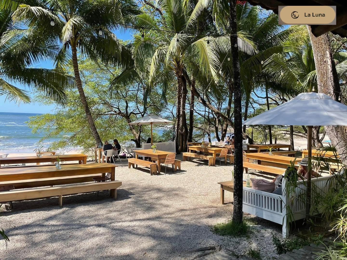 Beachfront teak tables under palms at La Luna in Playa Pelada, with the Pacific just steps away.